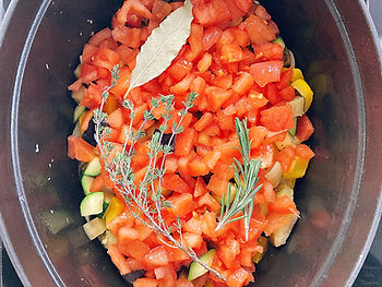 Zucchini, eggplant, yellow bell pepper, onion, garlic, tomato, bay leaf, thyme, rosemary in a pot