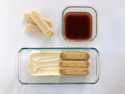 Mascarpone cream and biscotti savoiardi in a glass dish, black coffee and biscotti savoiardi in a glass container