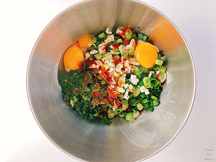 Eggs, spring onions, parsley, paprika powder, and pepper in a bowl