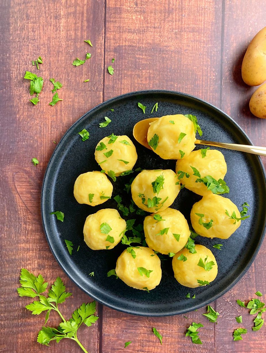 Potato dumplings, spoon, potatoes and parsley on a plate