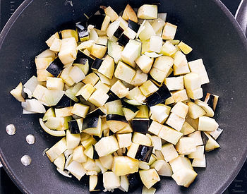 Eggplant, onion and garlic frying in a frying pan