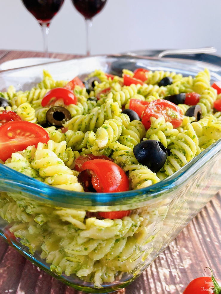 Genovese sauce pasta in a glass container, black olives, tomatoes, glasses with red wine and fork