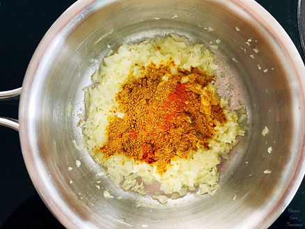 Onions, curry powder, chili powder in a pot,