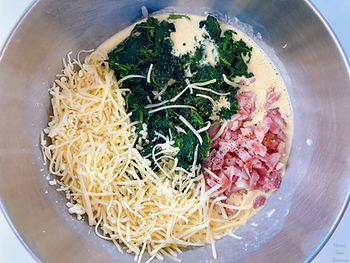 Eggs, crème fraiche, bacon, spinach and cheese in a bowl