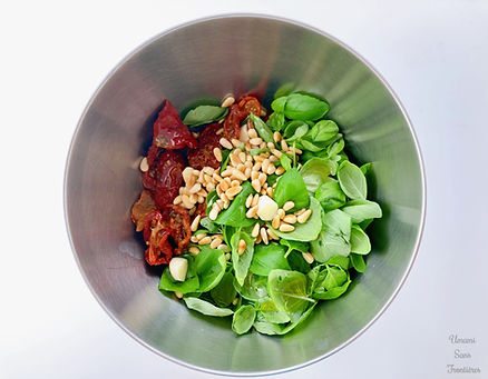 Basil leaves, sundried tomatoes, pine nuts and olive oil in a bowl