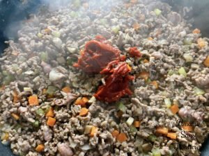 Bolognese vegetables bacon ground meat and tomato paste in a flying pan