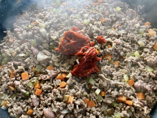 Bolognese vegetables bacon ground meat and tomato paste in a flying pan