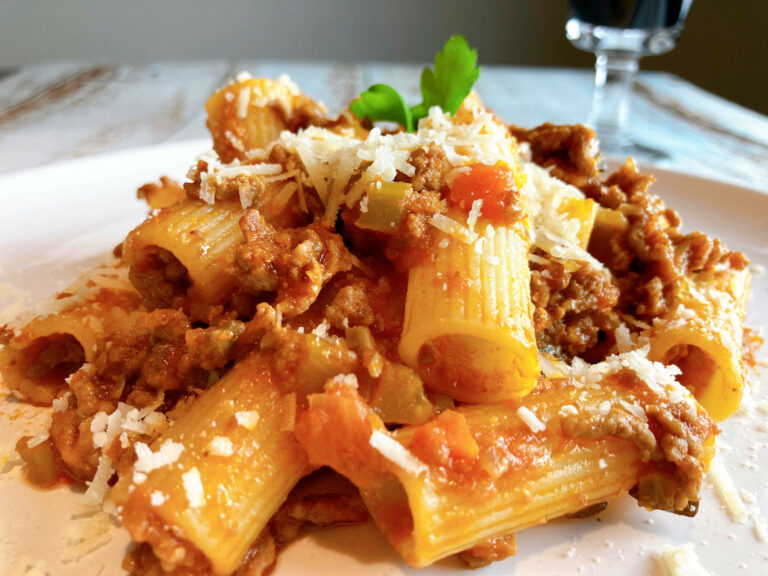 Bolognese bolognese pasta in a white dish red wine in a glass