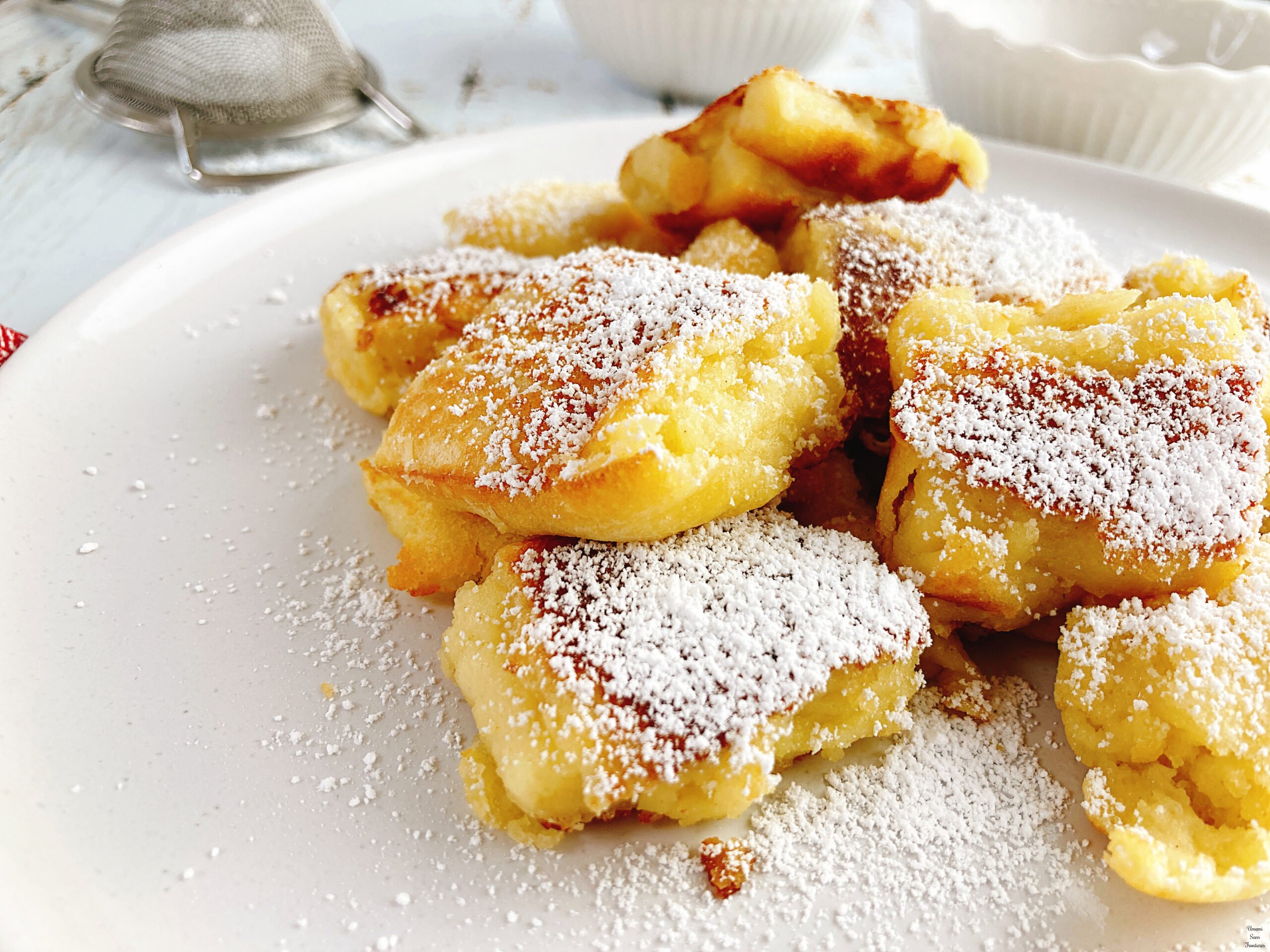 Kaiserschmarrn pancakes with powder sugar in a white plate and a tea strainer