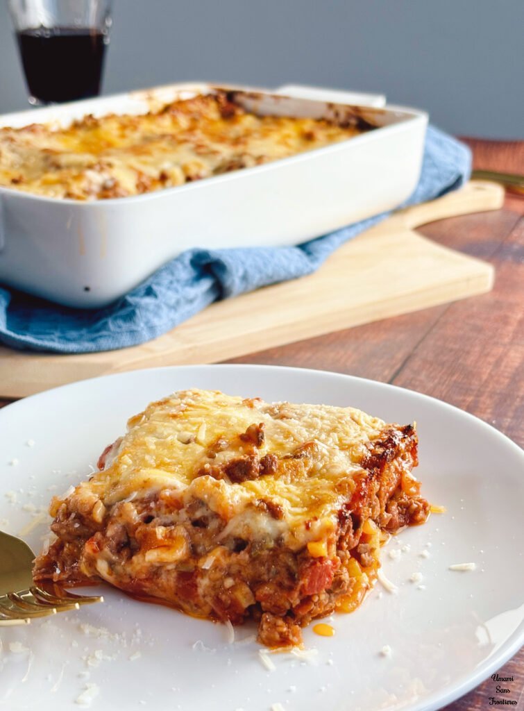 Lasagne lasagne on a white plage folk lasagne in a ovenproof dish dish towel wooden plate red wine wine glass