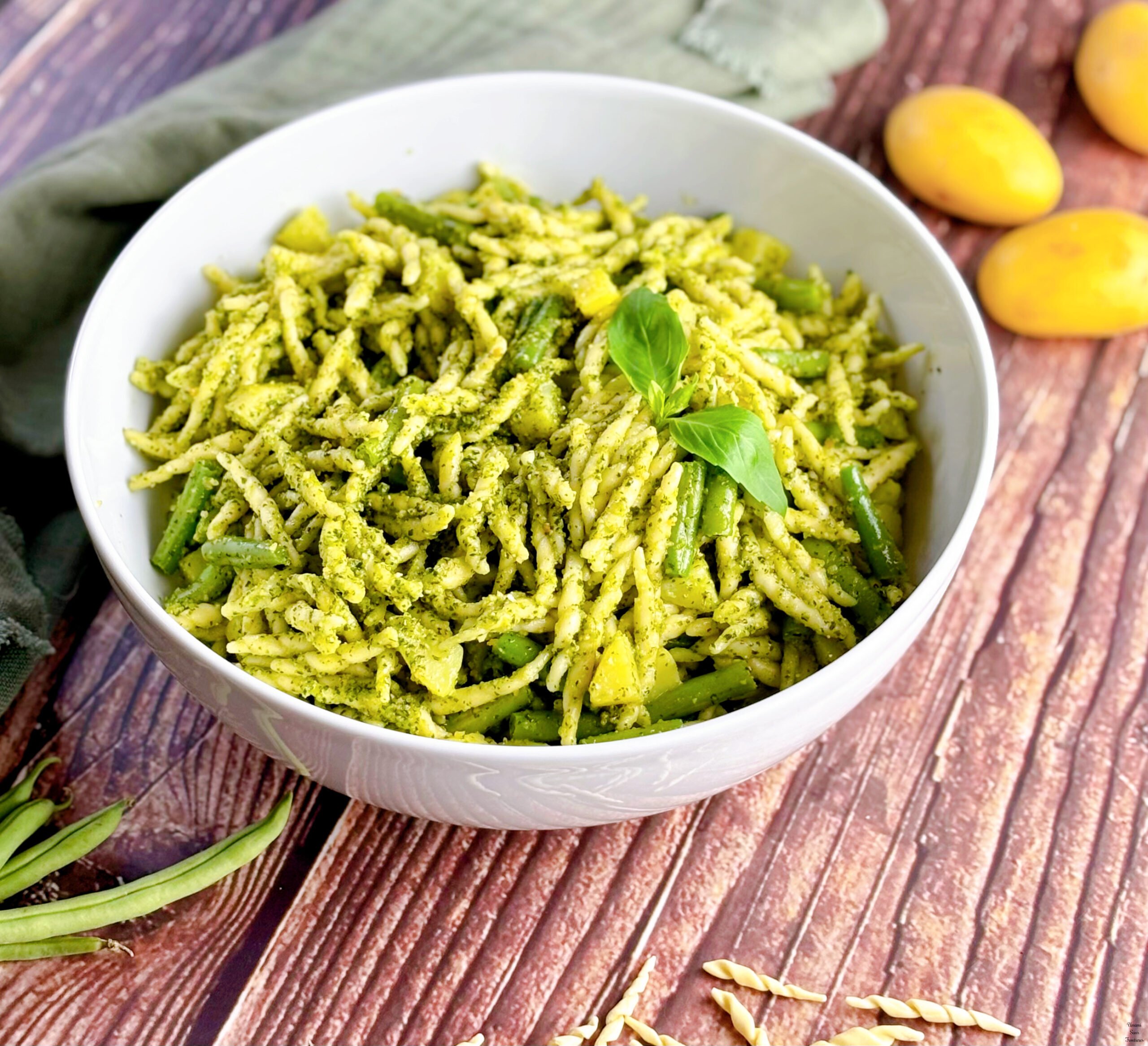 Pasta Pesto pasta torofie with pesto potatoes and green beans basil leaves in a white bowl_potatoes green beans a green napkin on the table