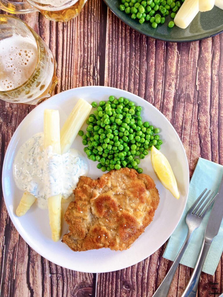 Schnitzel green peas white asparagus yogourt sauce lemon beer fork knife