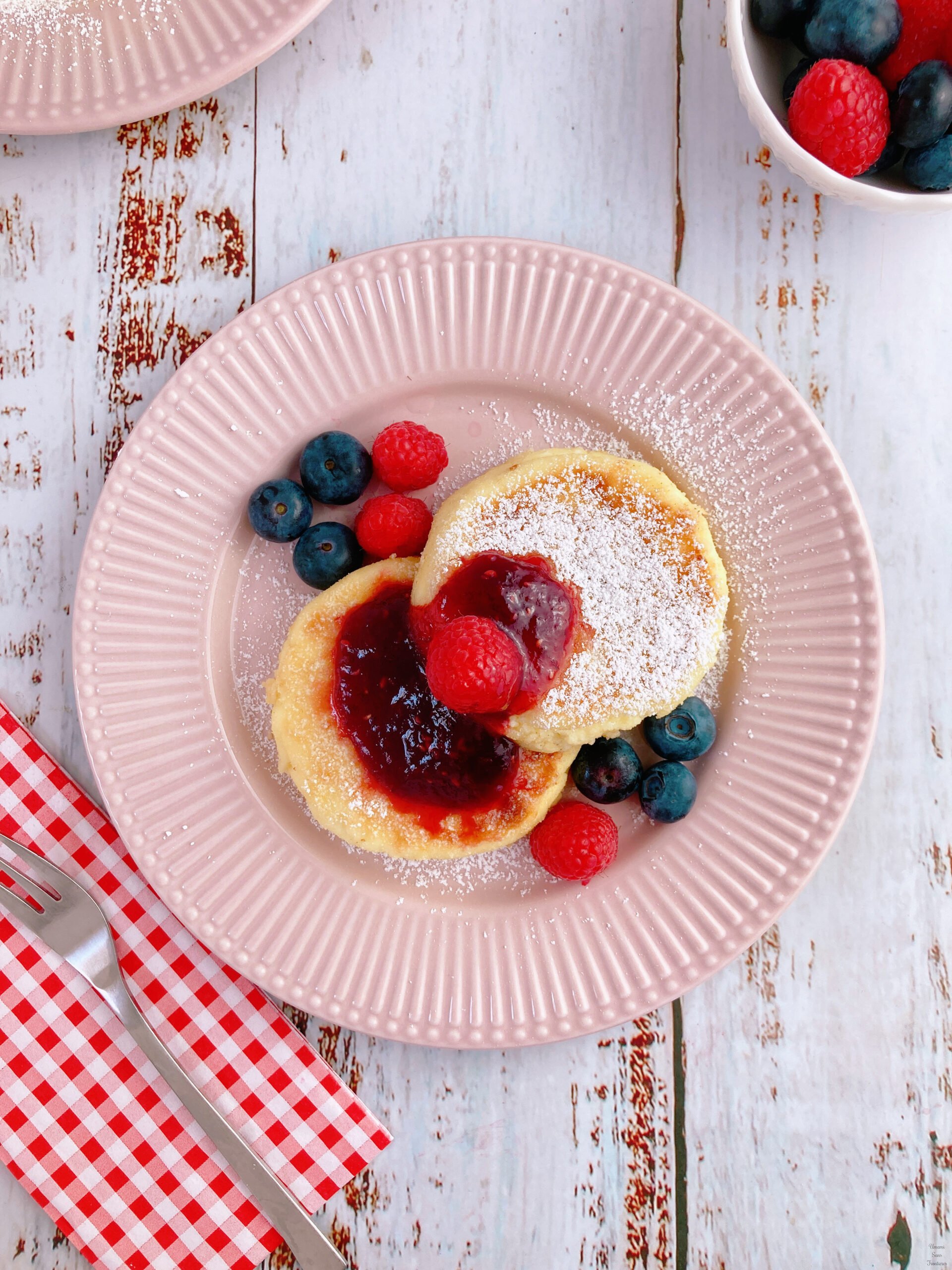 Syrniki pancakes raspberries blueberries jam powdersugar sugar fork
