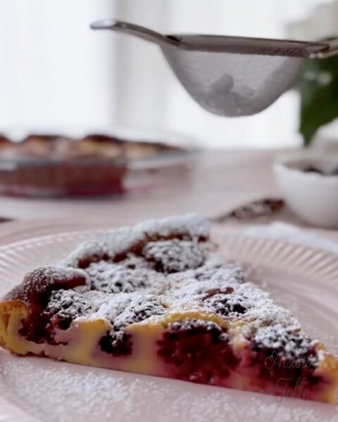 a piece of blackberry clafoutis icing sugar